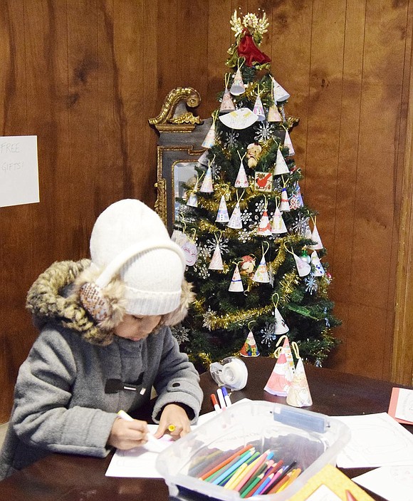 Five-year-old Flavia Aparcana of Irving Avenue colors a paper ornament to hang on the Christmas tree behind her.