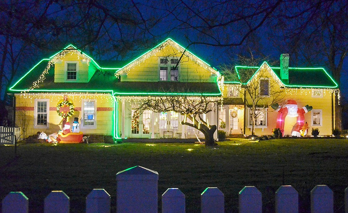 The tree in front of 11 Elm Hill Dr. weeps with the joy of the holidays, its artificial icicles fake-dripping in the dark. A few Santas line either side of the residence, and the roof features strands of color-changing lights that complement the other decorations.