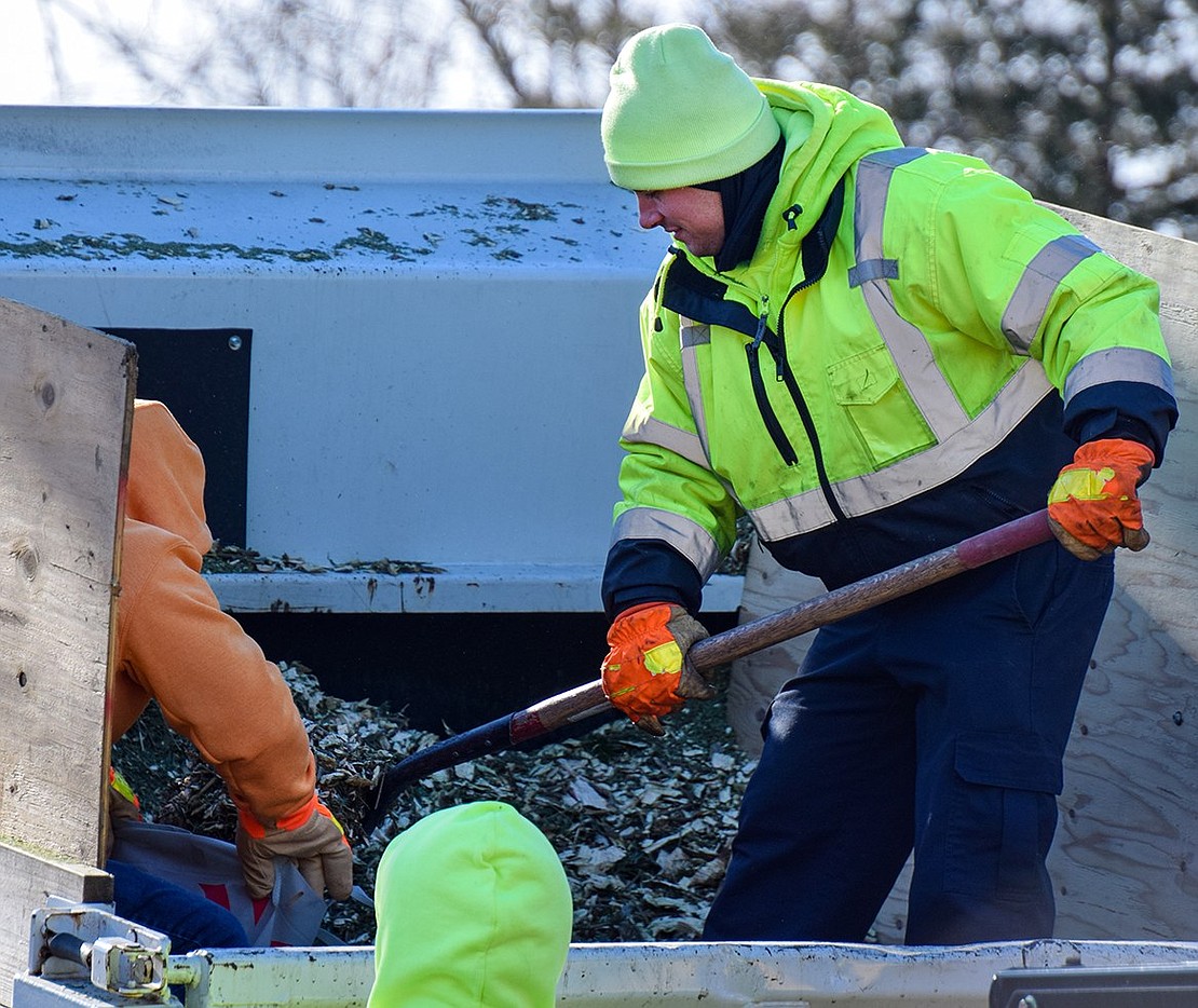 Port Chester Department of Public Works employee PJ Cambriello shovels mulch into bags, which were distributed to families who brought their trees to Lyon Park for chipping.