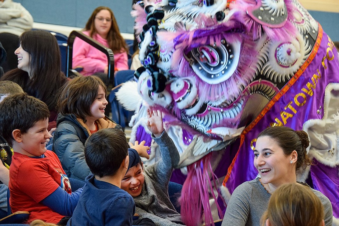 Performers from the Chinatown Community Young Lions, an organization based in New York City, nuzzle Ridge Street Elementary School third-grader Liam Deleon, who shies away from the cuddly onslaught before succumbing in a fit of giggles. The act was part of a Lunar New Year assembly in the school’s cafetorium on Wednesday, Jan. 18.