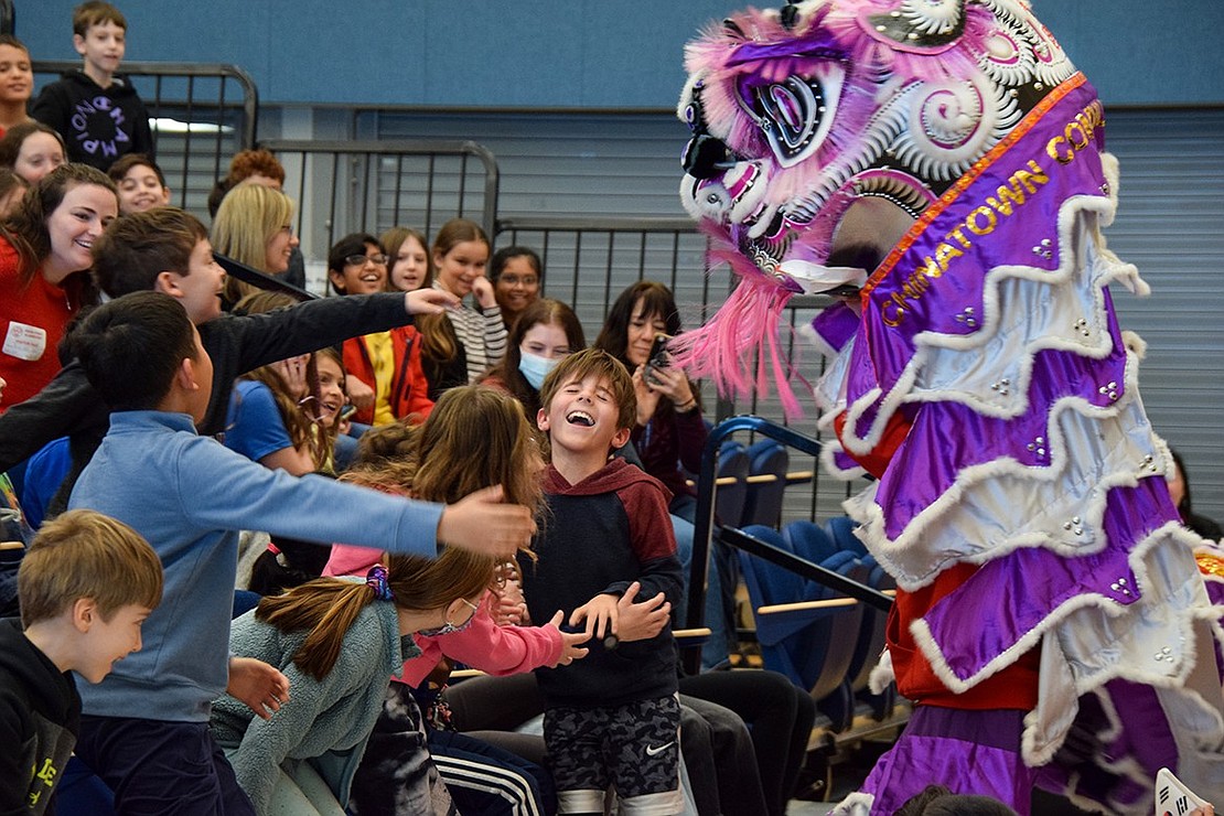 Third-grader Eli Ferrari runs into the arms of his ecstatic classmates after being chased across the cafetorium by the lion. He saw the colorful beast eating some of his peers, and he didn’t want to suffer the same fate.