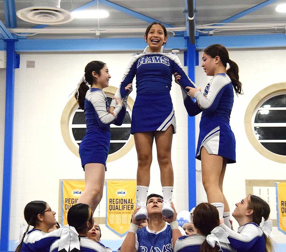 Junior varsity cheer members freshman Amy Navas (left), eighth grader Sophie Da Silva and sophomore Morgan Saunders get propelled high as they pose in their air for a stunt.