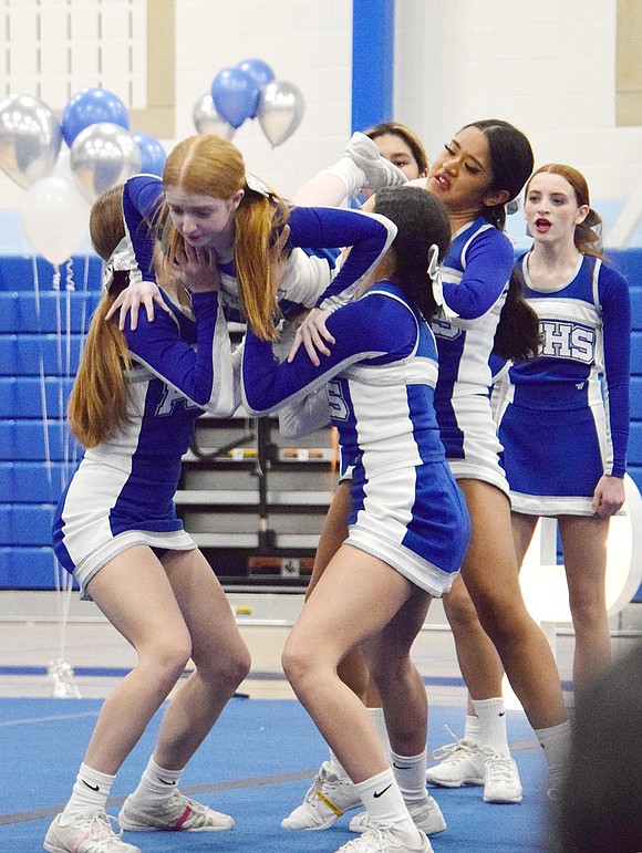 Varsity cheerleader Kelly Pascale, a freshman, trusts her squad enough to land into their arms after performing an elevated stunt.