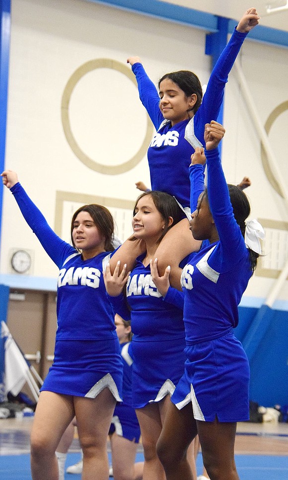 Perfecting the form, modified cheer team members strike a pose. Eighth-grader Josselyn Pallashco acts as the base holding Madison Mollica, a seventh-grader, on her shoulders while seventh-grader Emelin Diaz (left) and eighth-grader Kylie Grant stand to the sides.