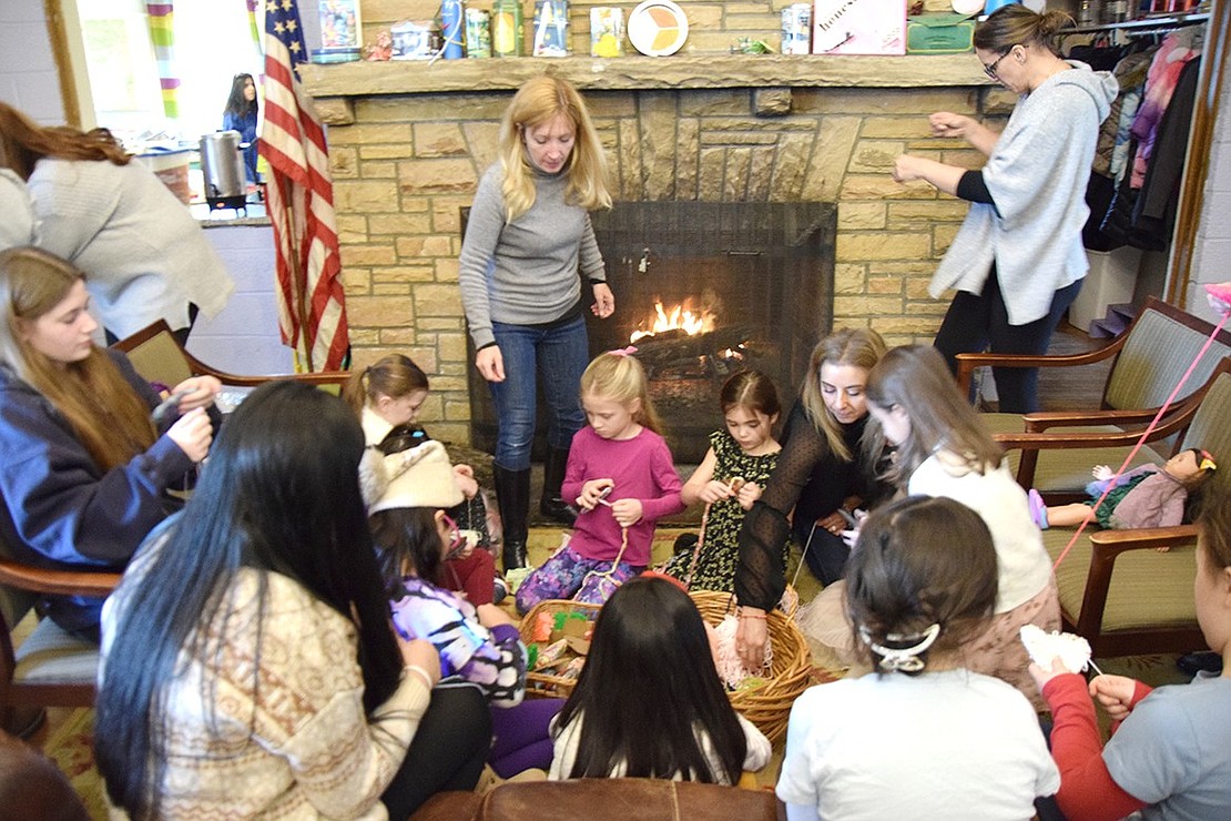 After snacking on baked goods and drinking herbal refreshments, a group of girls gather around the fireplace for crafts, making yarn wrapped hearts that were used to decorate the Girl Scout House.